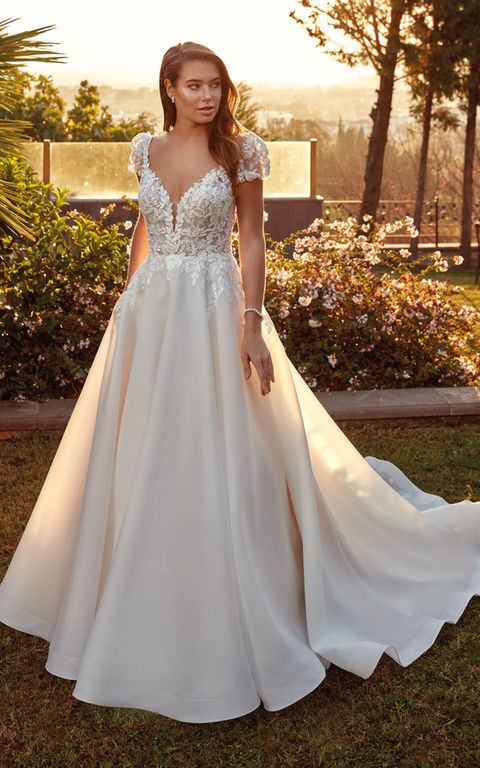 outdoor photo of woman wearing white designer eddy k wedding dress